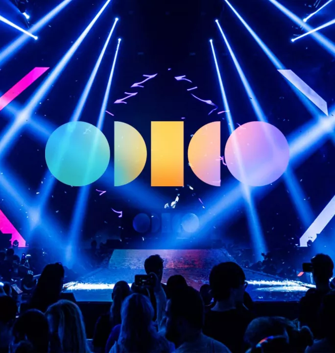 Odido logo on a picture of stage with moving LED beams.